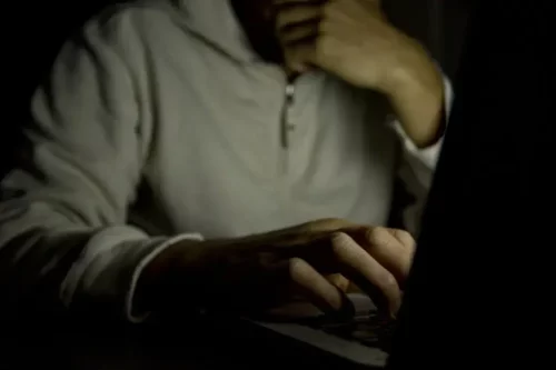 Mand sidder i mørke med computer