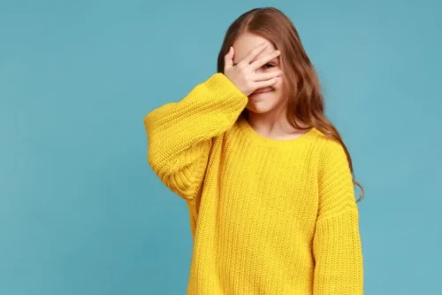 Pige skjuler sit ansigt og repræsenterer, hvordan du følelsesmæssigt invaliderer dig selv