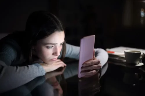 Teenager ser på telefon i mørke