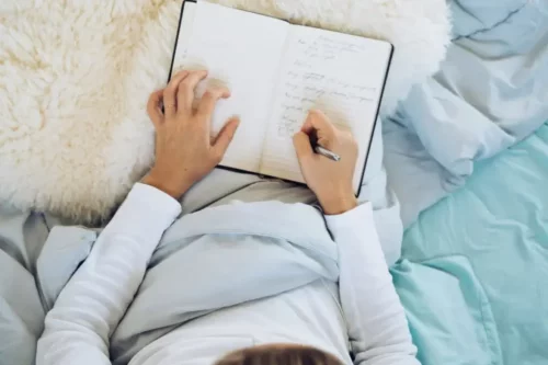 Kvinde skriver dagbog i seng