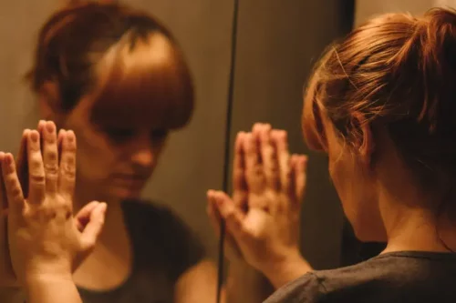 Kvinde placerer sine hænder på et spejl