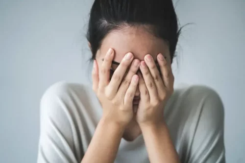 Kvinde skjuler ansigt bag sine hænder og repræsenterer personer med depression