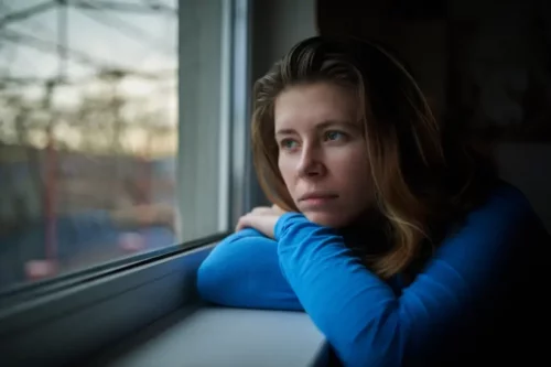 Kvinde ser ud af vindue og tænker over stresshåndtering