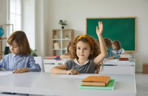 Pige rækker hånden op i skolen