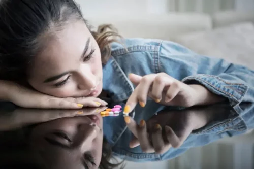 Trist teenager med piller på bord foran sig