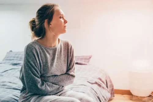Ulykkelig kvinde sidder på seng og er offer for sammenlignende lidelse