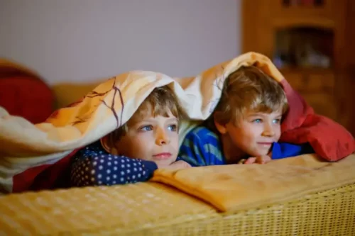 Drenge ser fjernsyn under et tæppe