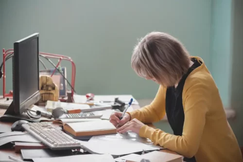 Kvinde sidder og skriver ved skrivebord