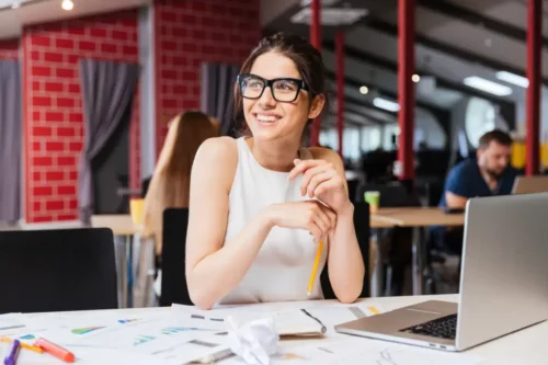 Smilende kvinde på arbejdsplads repræsenterer høj psykologisk kapital