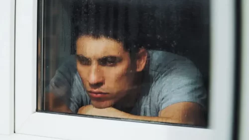 Trist mand ser ud af vindue