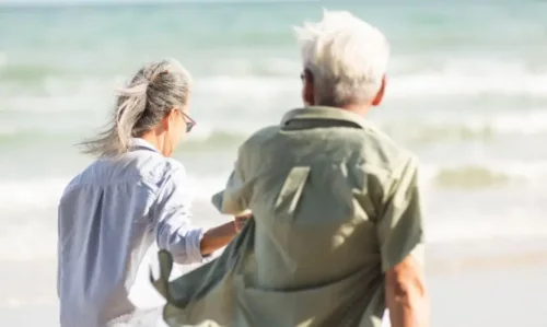 Ældre par går sammen på strand, selvom vi bliver mere indadvendte med alderen