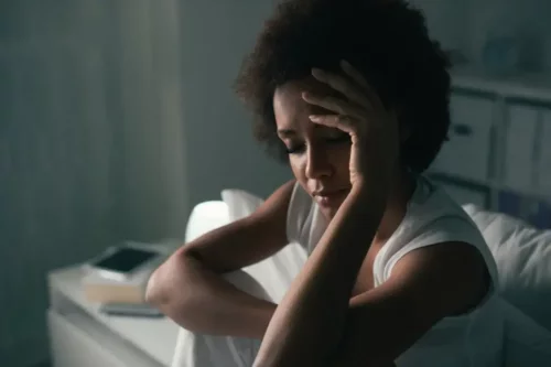 Kvinde i seng tager sig til hovedet og repræsenterer neurobiologien bag OCD