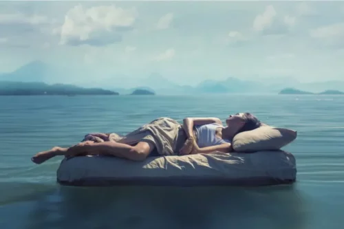 Kvinde sover på luftmadras på sø