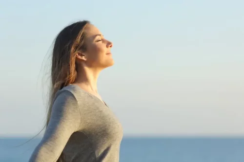 Kvinde står og nyder solen og udfører grounding, som er en af de kropscentrerede teknikker i terapi