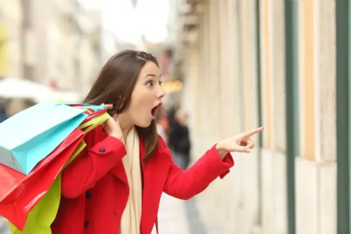 Kvinde shopper og kigger overrasket på butiksvindue