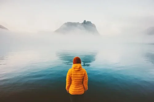 Person står og ser på en sø
